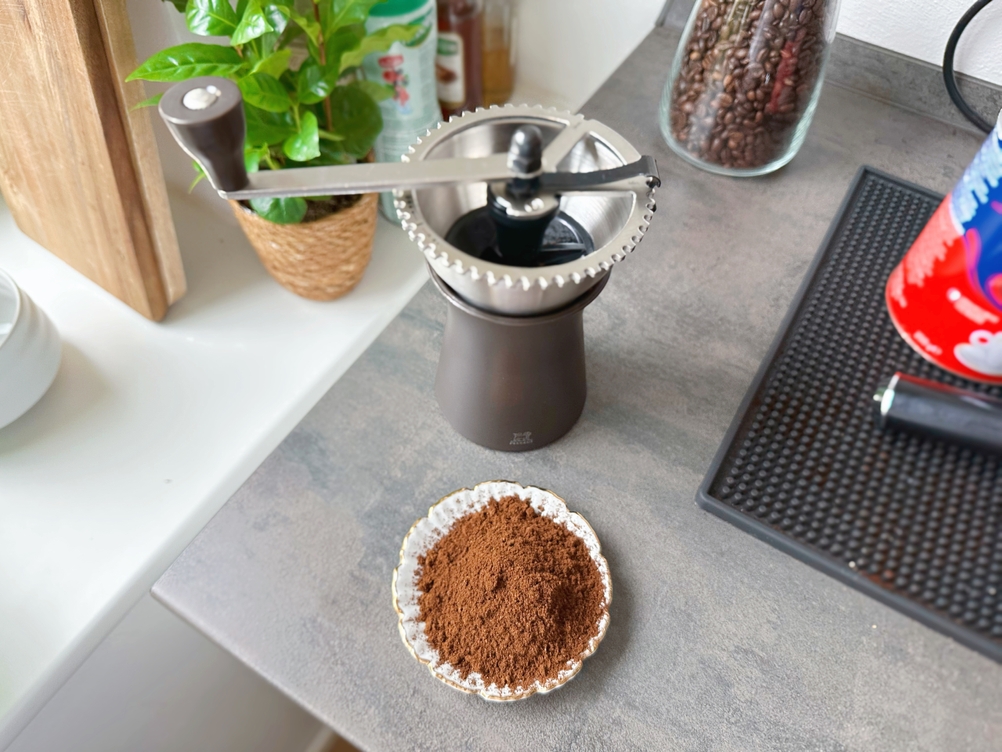 Handkaffeemühle Kronos getestet: Das fertige gemahlene Kaffeepulver der Mühle von Peugeot lieft vor ihr auf einem kleinen Teller.