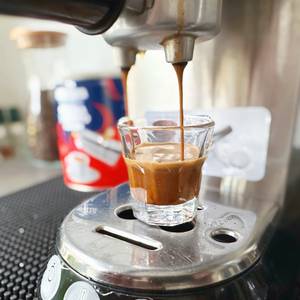 Handkaffeemühlen im Test: Aus einer Siebträgermaschine fließt Espresso in ein Glas.