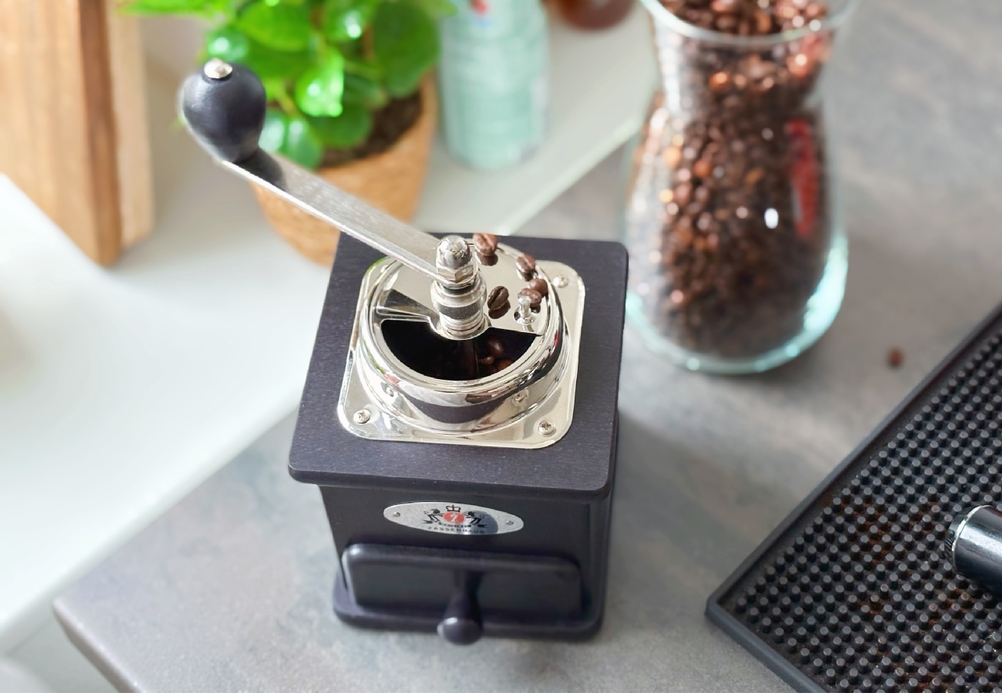 Handkaffeemühle im Test: ein paar Bohnen liegen auf dem Bohnenbehälter einer Kaffeemühle.