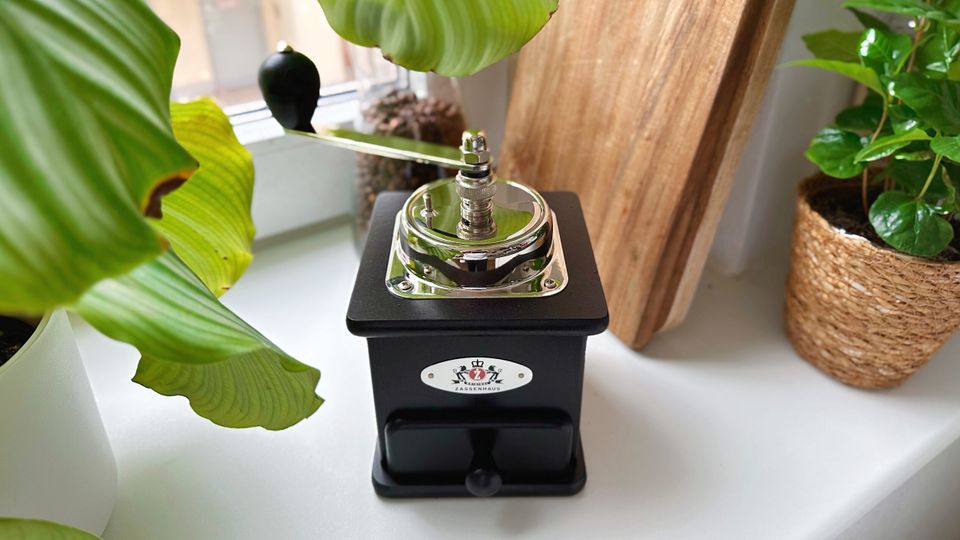 Handkaffeemühlen im Test: Eine Retro-Kaffeemühle von Zassenhaus steht dekorativ auf der Fensterbank.
