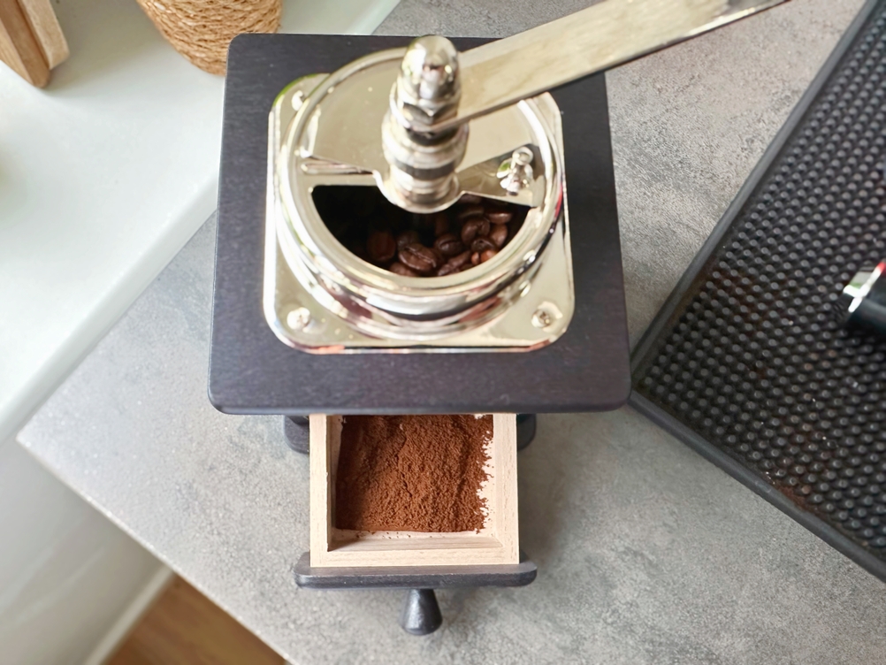 Handkaffeemühlen im Test: Der Auffangbehälter der Brasilia ist herausgezogen, etwas Kaffee ist darin.