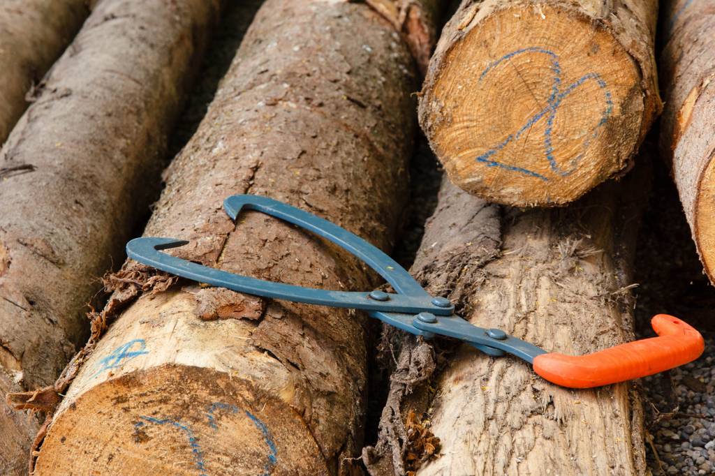 Handpackzange im Test: Eine Handpackzange liegt auf einem Stapel von Holzstämmen.