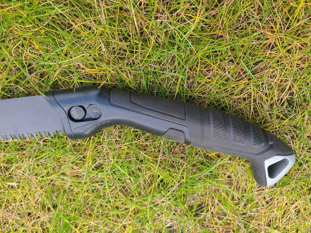 Nahaufnahme des Griffes der Handsäge im Test auf Rasen liegend.