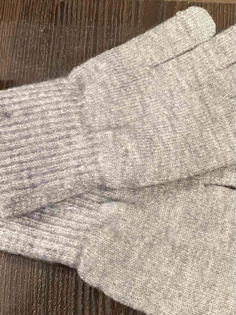 Handschuhe-Damen-Test: Hellgraue Handschuhe liegen auf einer Holzfläche.