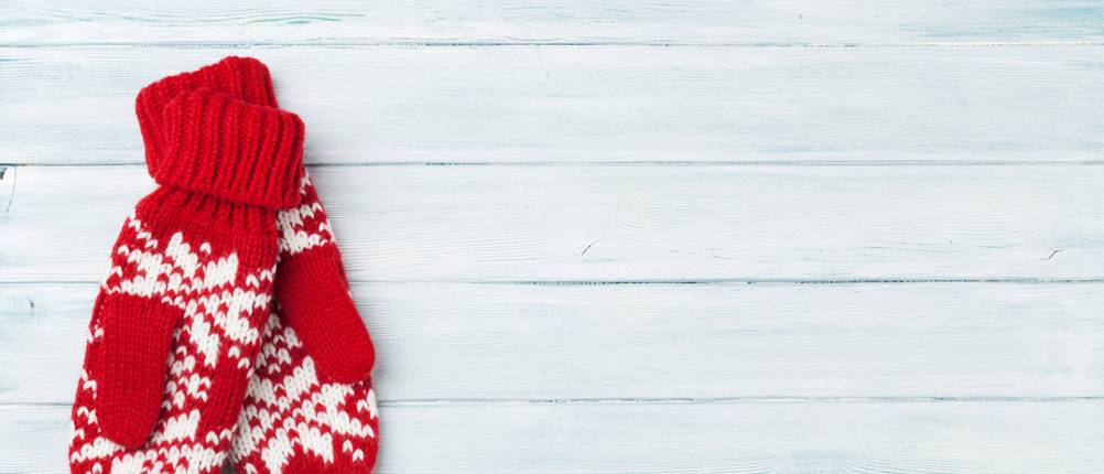 zwei rote Winterhandschuhe aif einem Holzboden