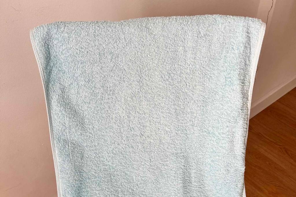 Handtücher im Test: ein mintfarbenes Handtuch mit Stickerei hängt über einem Stuhl.
