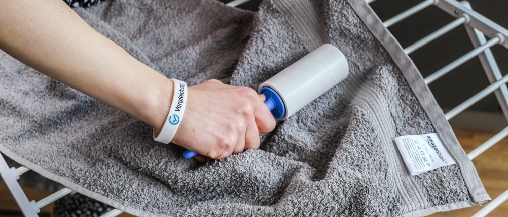 Eine Hand führt einen Fusselroller über ein Handtuch.