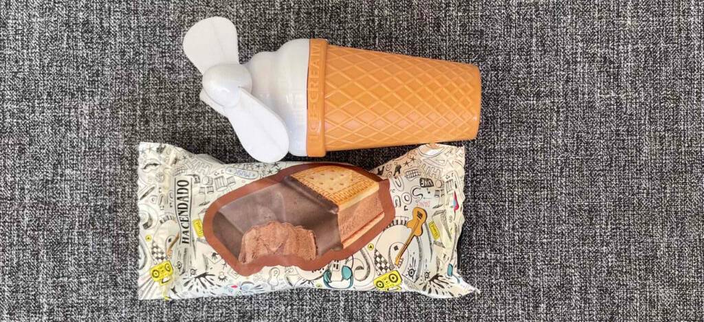 Nahaufnahme eines getesteten Handventilators im Eishörnchen-Design neben einer verpackten Eiswaffel.