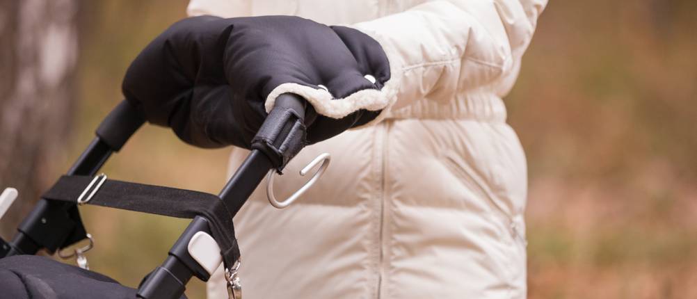 Handwärmer für Kinderwagen im Test: Frau schiebt KInderwagen mit Händen in schwarzem Handwärmer