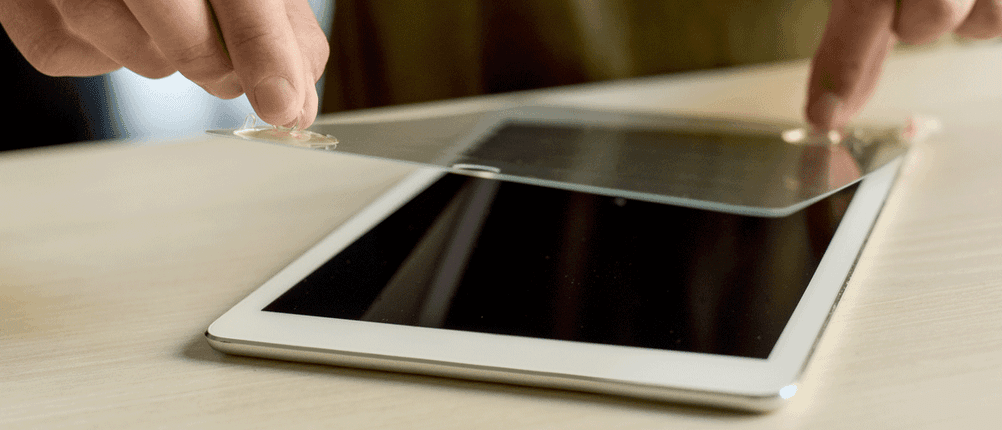 Mann legt Schutzfolie auf Tablet auf