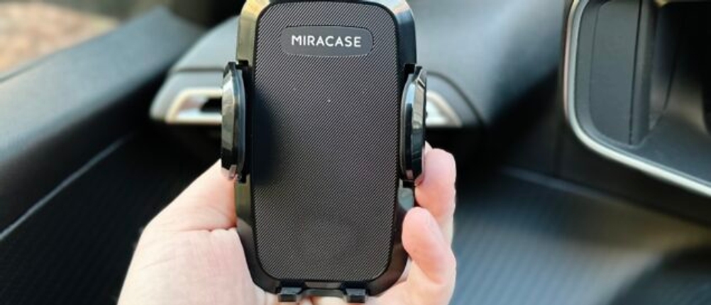 Die Auto-Handyhalterung von Miracase wurde in der Lüftung eines Autos montiert und eine Hand hält diese.