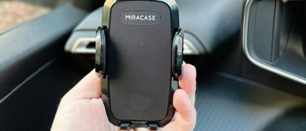 Die Auto-Handyhalterung von Miracase wurde in der Lüftung eines Autos montiert und eine Hand hält diese.