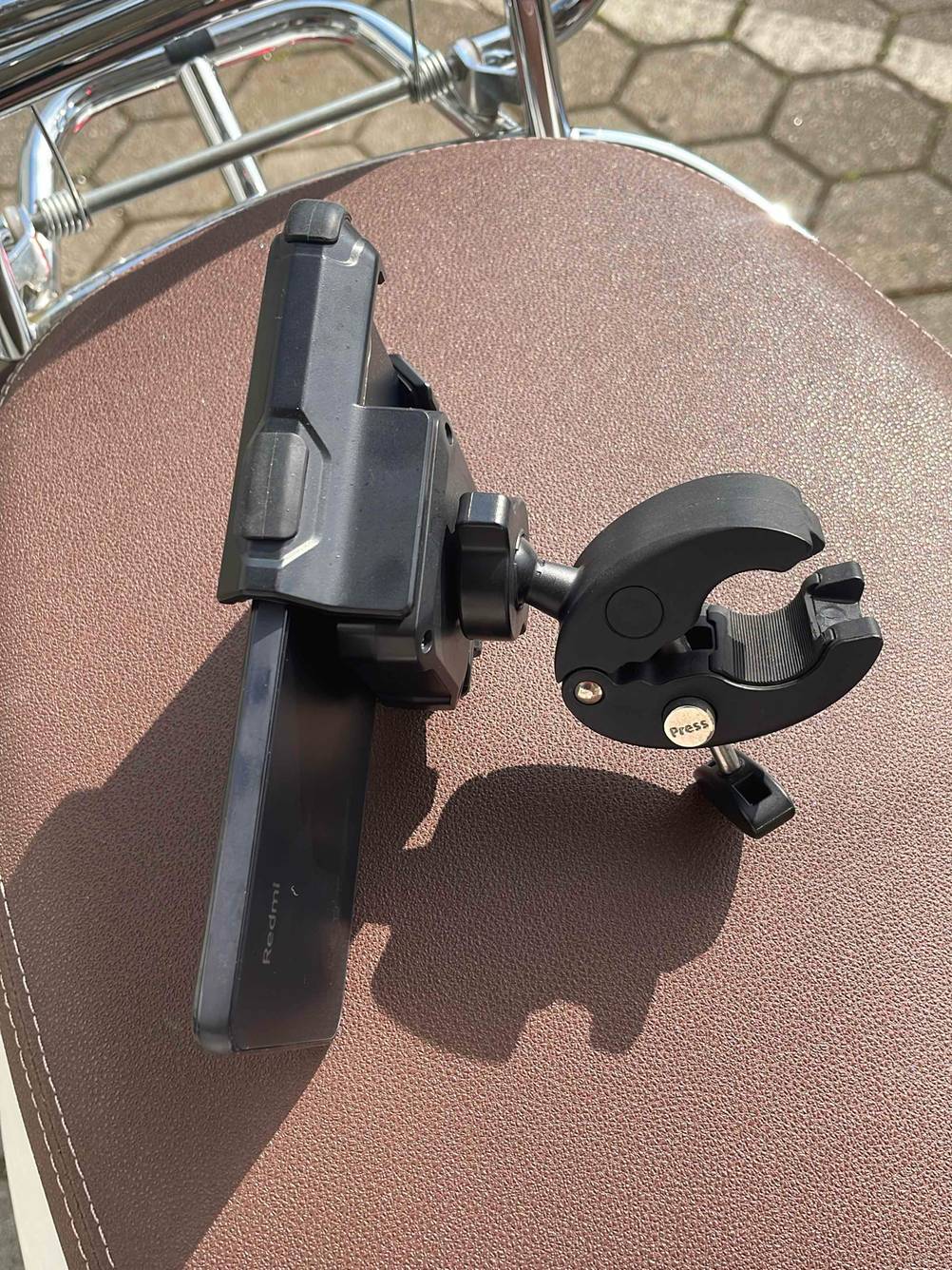 Getestet: Eine Handyhalterung für das Motorrad von der Seite mit Handy auf einem Ledersitz.