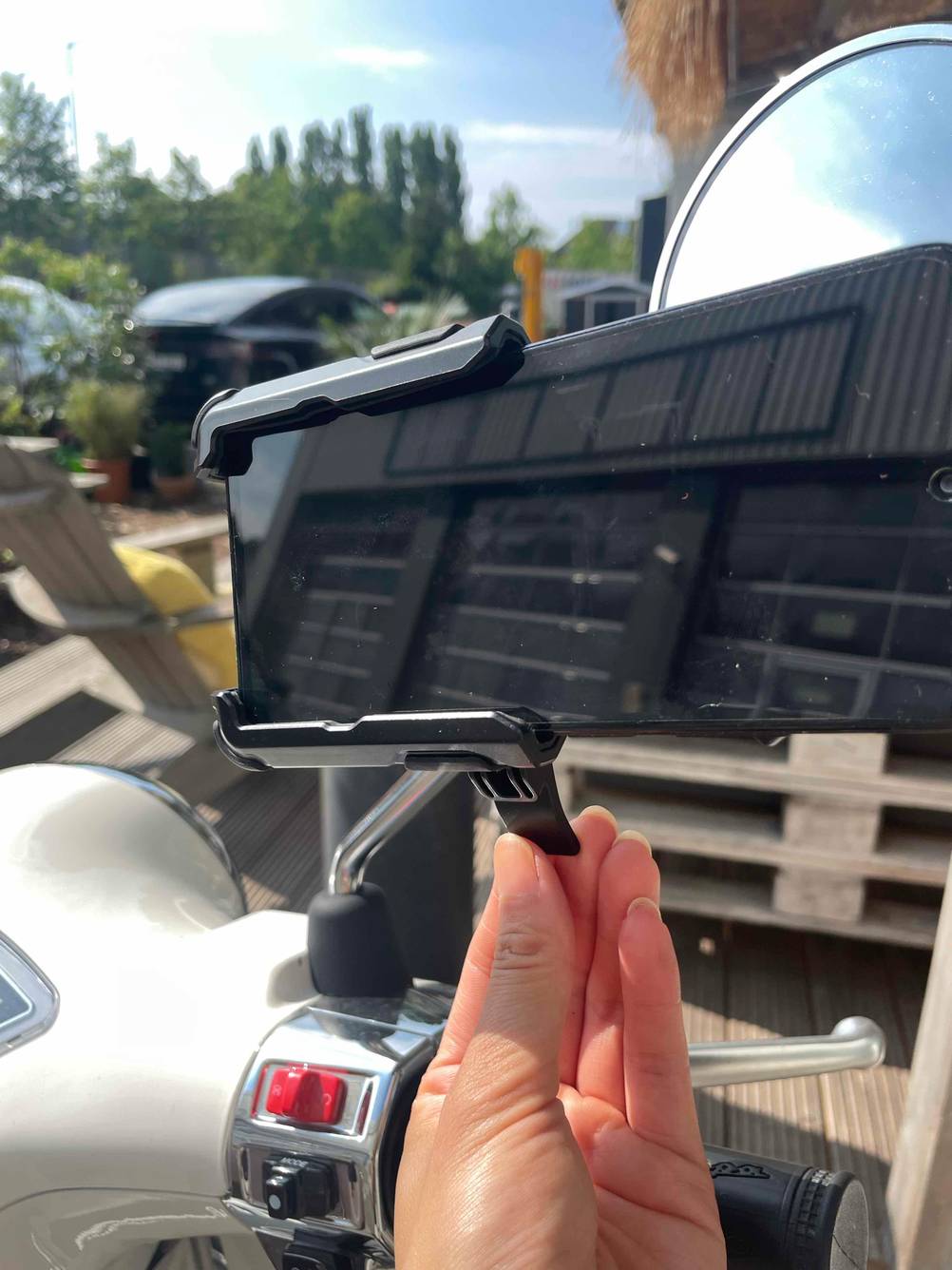 Eine Hand an der Schnellspannvorrichtung einer getesteten Handyhalterung für das Motorrad.