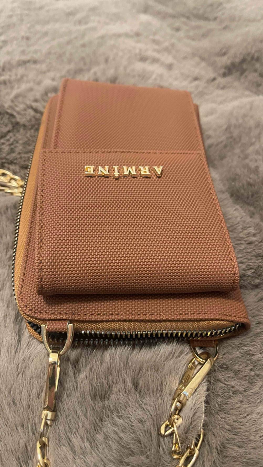 Die getestete Handytasche von oben auf einem grauen Fell liegend.