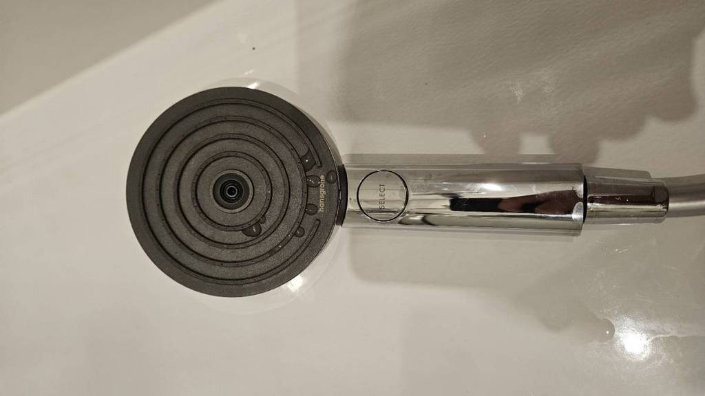 Nahaufnahme eines Hansgrohe Duschkopfs im Test, der auf einer hellen, nassen Oberfläche liegt.