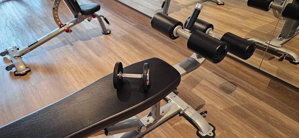 Eine getestete Hantelbank steht in einem großen Zimmer mit anderen Geräten.