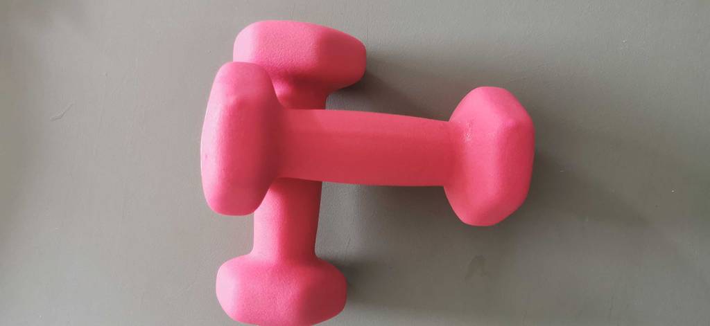 Zwei pinkfarbene 1 kg Hanteln, die überkreuz aufeinander liegen