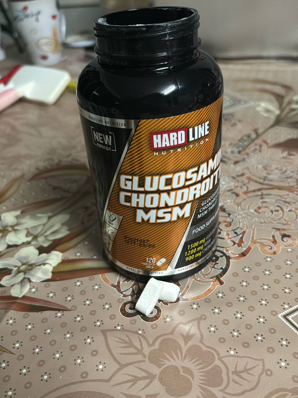 Vor einer geöffneten Flasche Glucosamin liegen zwei Tabletten zum testen.