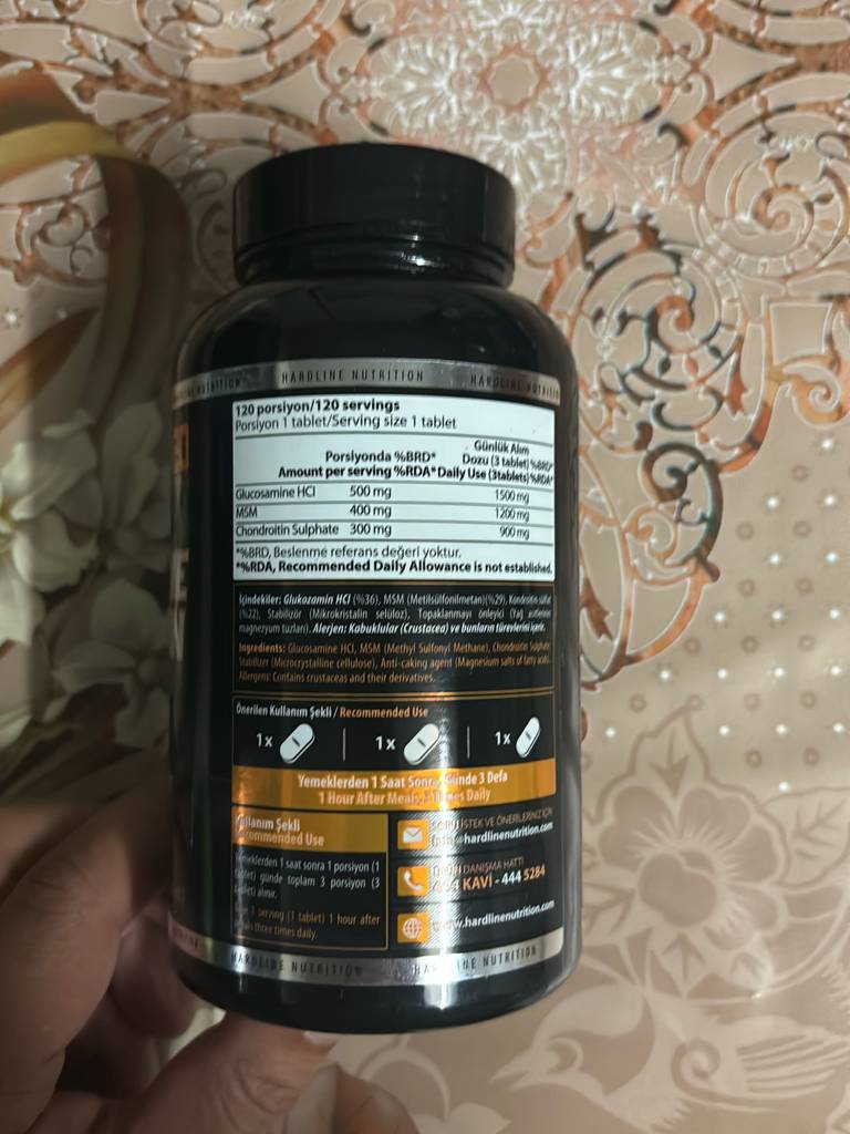 Glucosamin im Test: Nahaufnahme von einem schwarzen Flakon inklusive Produktetikett auf einer beige gemusterten Tischdecke.