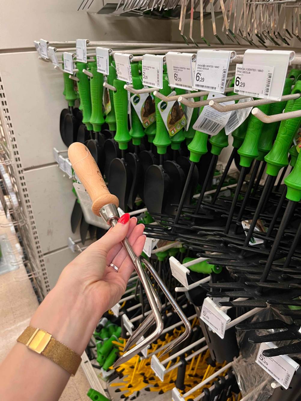 Eine Hand hält eine getestete Harke mit Holzgriff.
