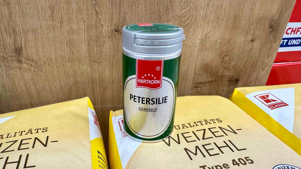 Petersilie getestet: Eine Dose steht auf einer Packung Weizenmehl vor einer Holzwand.