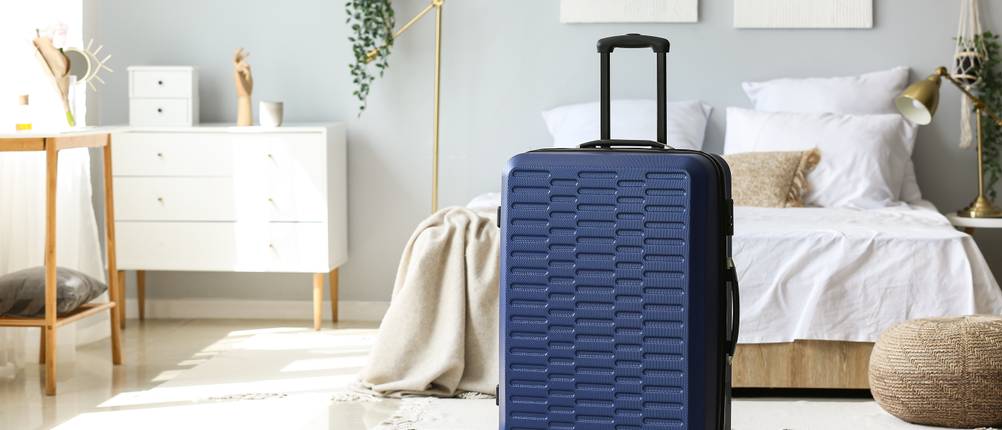 Hartschalenkoffer mit 65 cm Höhe im Test: blauer Koffer steht gepackt im Schlafzimmer.