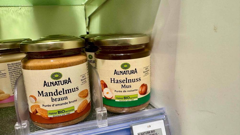 Im Verkaufsregal stehen mehrere Gläser des Haselnussmuses neben anderen Produkten.