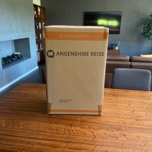 Der Karton des Hauptstadtkoffer Spree steht auf einem Holztisch.