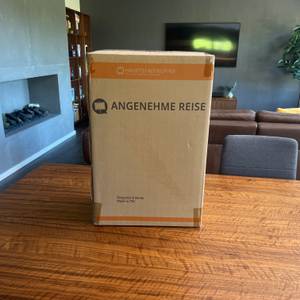 Der Karton des Hauptstadtkoffer Spree steht auf einem Holztisch.