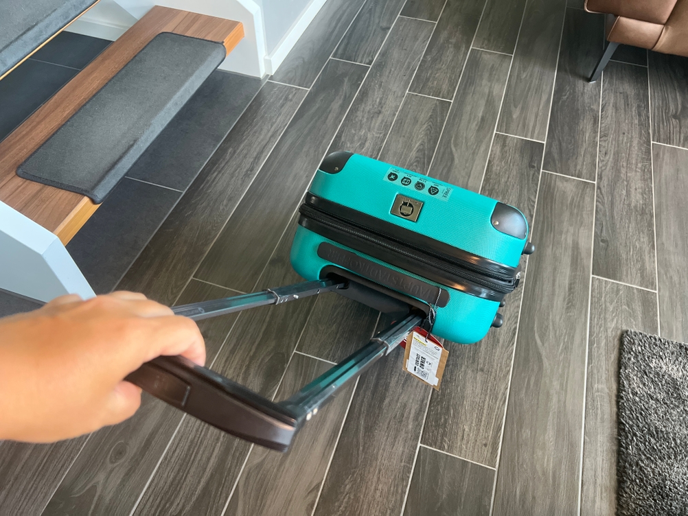 Der Hauptstadtkoffer Spree wird von einer Hand am Griff gehalten.