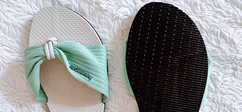 Ansicht von oben auf ein Paar mintgrüner Damen-Pantoletten im Test: eine Pantolette zeigt ihre schwarze Profilsohle.