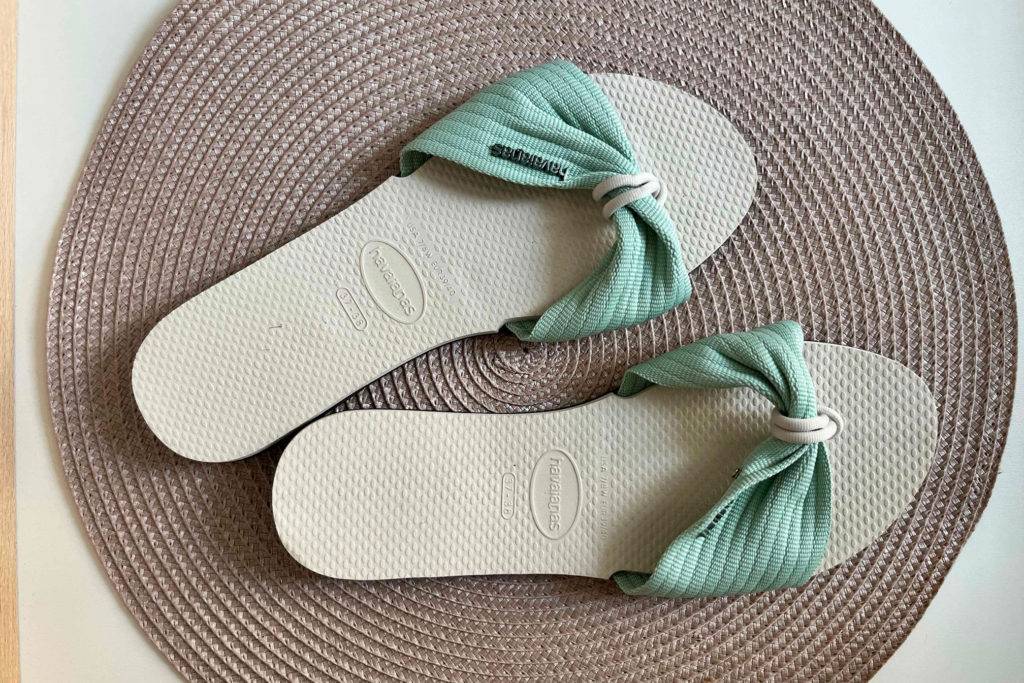 Pantoletten für Damen im Test: Paar in mintgrün in Größe 37/38 von Havaianas steht auf rundem dunklen Häkelteppich.