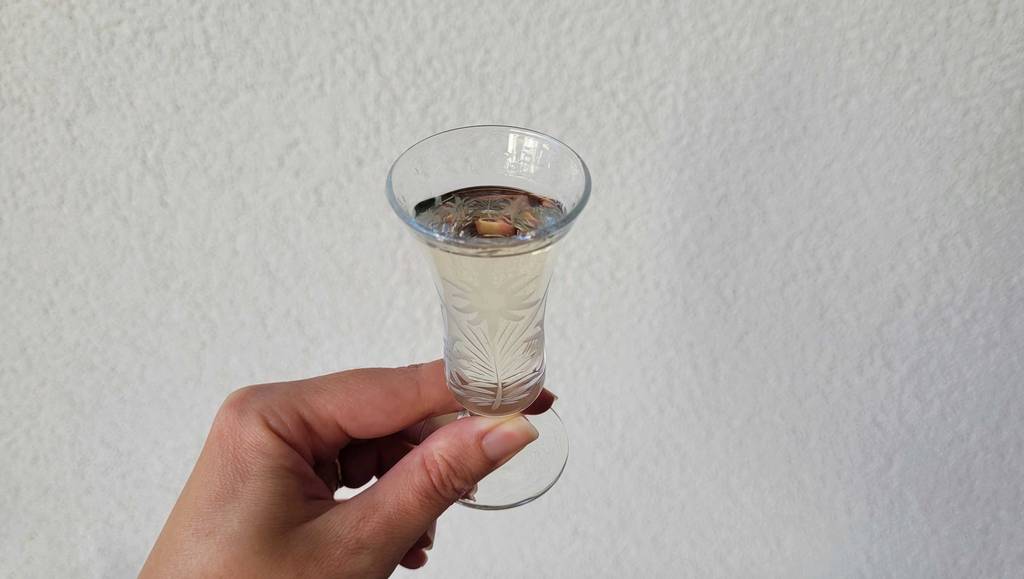 Eine Hand hält ein gefülltes Glas Weißer Rum zum testen.