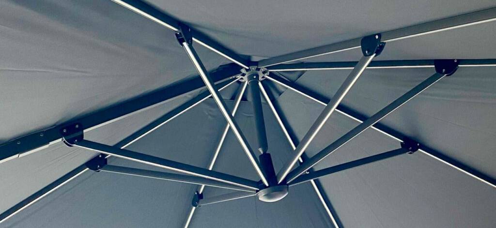 Detailansicht von unten auf das beleuchtete Gerüst eines anthrazitfarbenen Ampel-Sonnenschirms mit LED im Test.