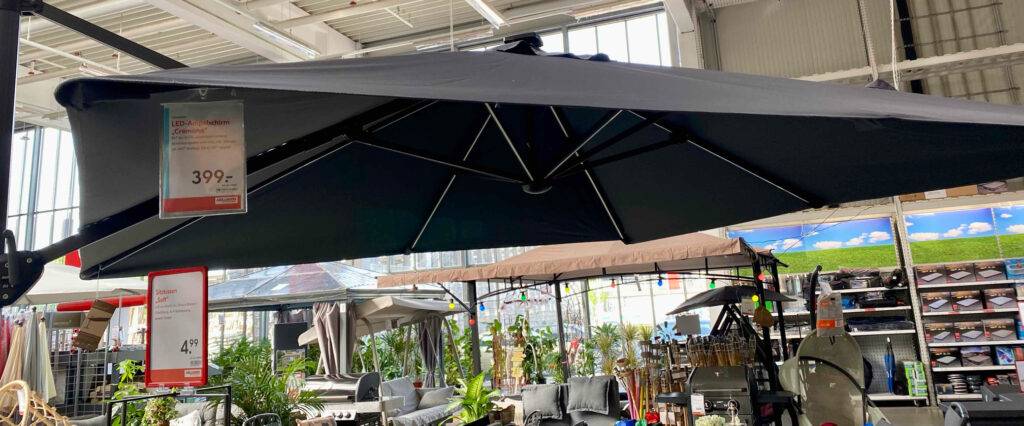 Sonnenschirm mit LED im Test: ein anthrazitfarbener Ampelschirm inklusive Preisschild ist in einem Baumarkt ausgestellt.