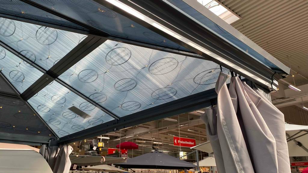 Getestet: ein Pavillon aus Metall, mit Fokus auf den Dachbereich, mit Montageschiene für den angebrachten anthrazitfarbenen Vorhang.