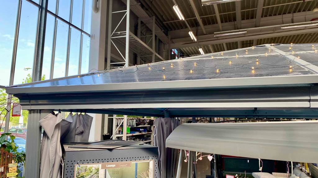 Pavillon-Metall im Test: Ansicht des Daches inklusive Lichterketten-Beleuchtung eines im Gartencenter aufgebauten, grauen Pavillons.