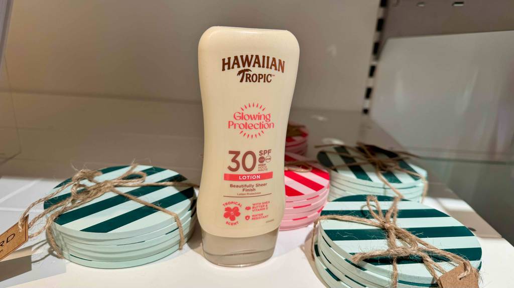 Eine Flasche Hawaiian-Tropic-Sonnencreme steht zum testen zwischen bunt gestreiften Untersetzer-Sets.
