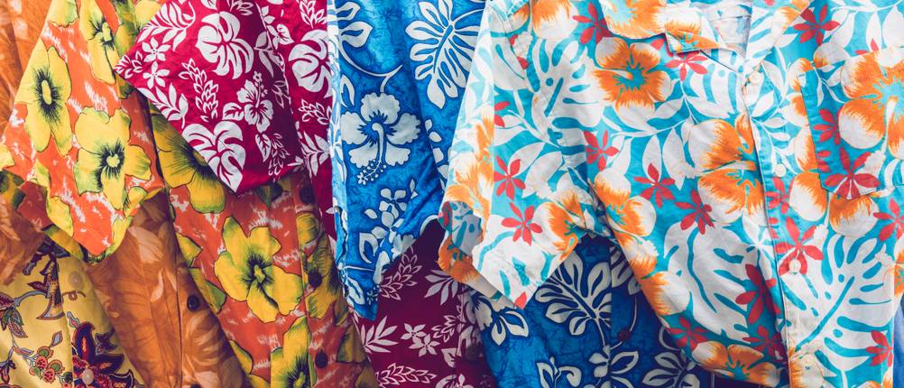 Hawaiihemd im Test: Mehrere bunte Hawaiihemden sind nebeneinander auf Bügeln aneinandergereiht.