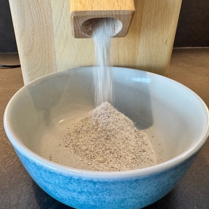 Getreide wird in der Hawos-Mühle 1 gemahlen und fällt in eine Schale