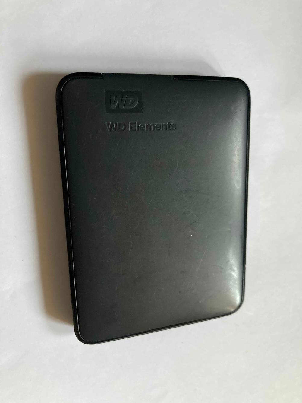 Eine schwarze HDD-Festplatte im Test auf einer hellen Fläche von oben.