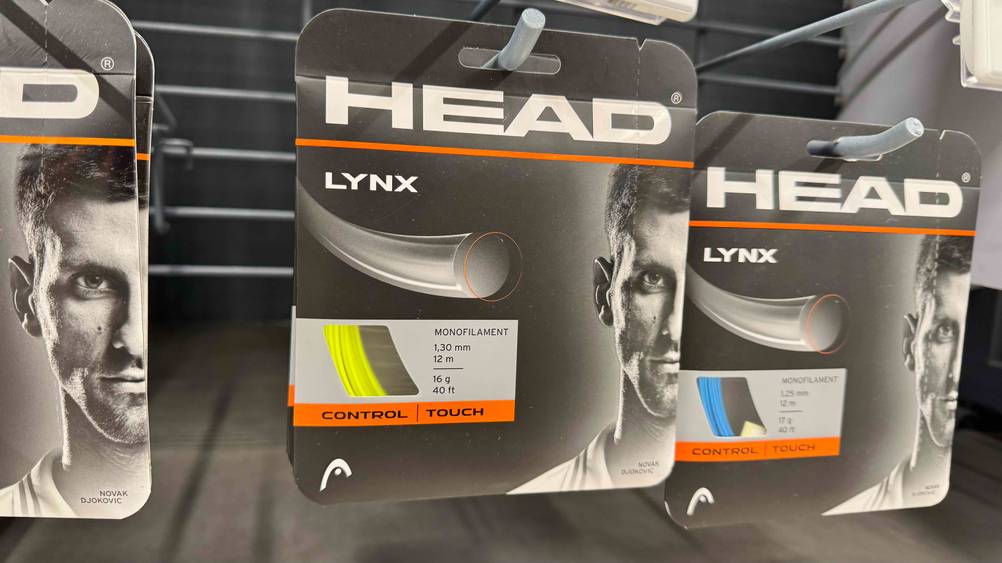 Mehrere Packungen der HEAD-Tennissaiten im Test hängen in einem Regal.