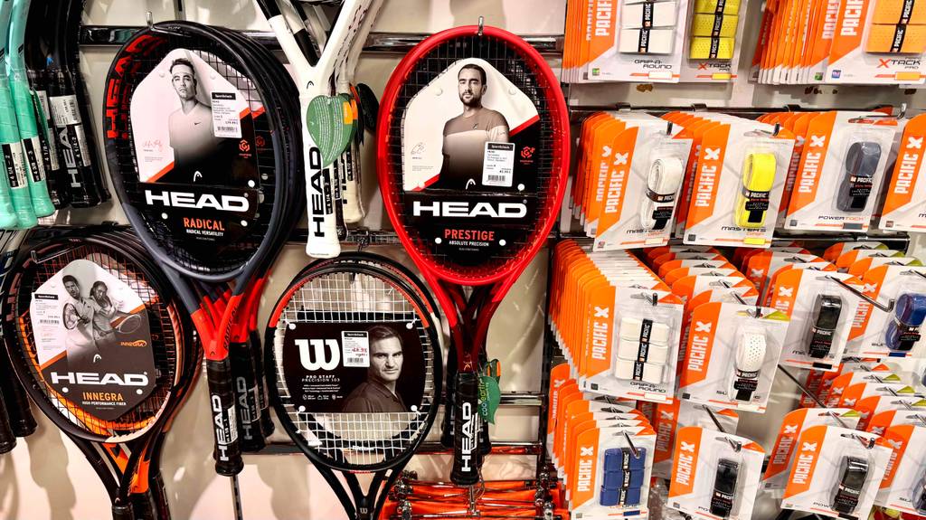 Head-Tennisschläger im Test: Mehrere Schläger in unterschiedlichen Ausführungen hängen an einem Regal.
