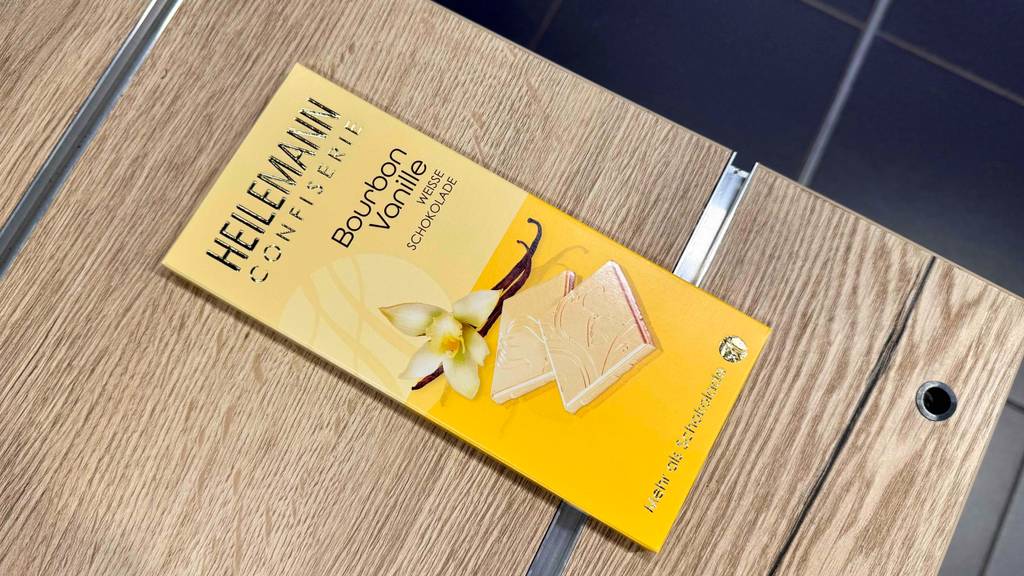 Eine weiße Schokolade im Test liegt in ihrer Verpackung auf einem Holztisch.
