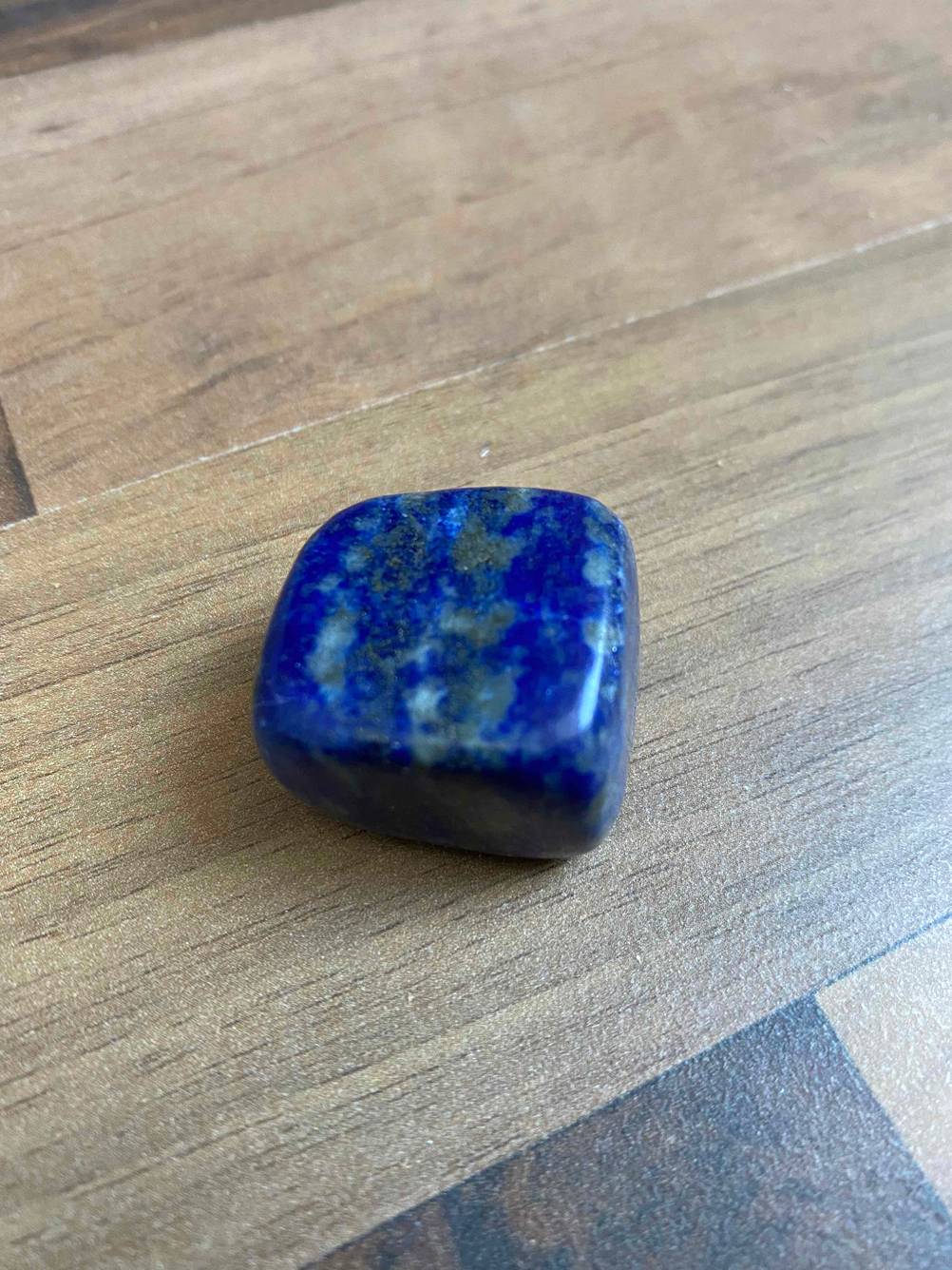 Ein getesteter blauer Heilstein liegt auf einer Holzfläche.