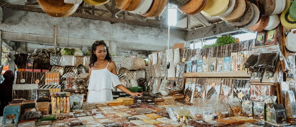 Verkäuferin steht hinter einem Stand auf einem Wochenmarkt.