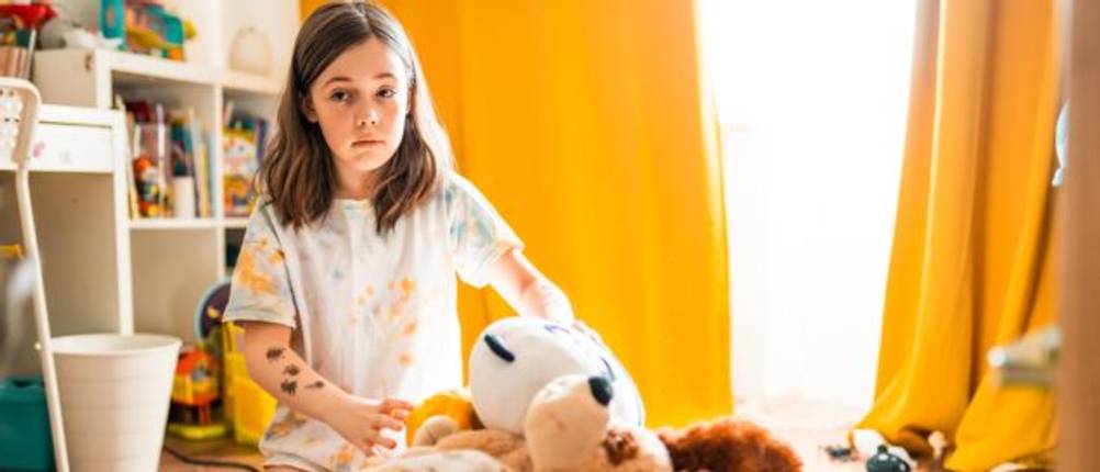 Junges Mädchen räumt Kuscheltiere in einen dafür vorgesehenen Beutel.