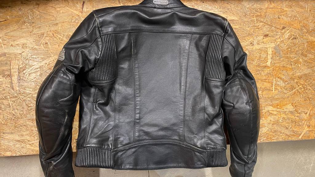 Motorradjacken für Damen im Test: Schwarze Lederjacke von hinten vor einem Holzhintergrund.