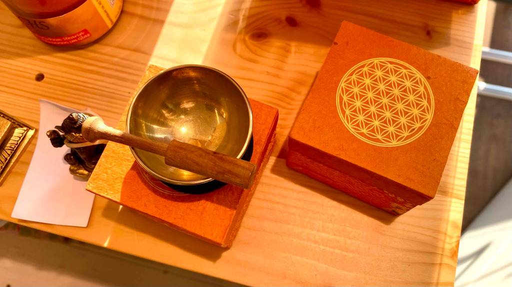 Klangschale-Test: Zwei Boxen auf einem Holztisch, auf einer steht eine Klangschale mit Klöppel.